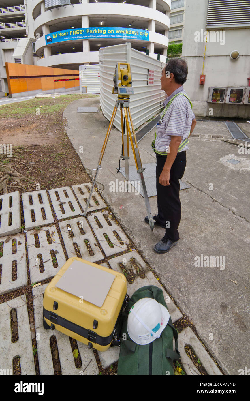 Un geometra al lavoro con la Stazione Totale strumento topografico in Singapore Foto Stock