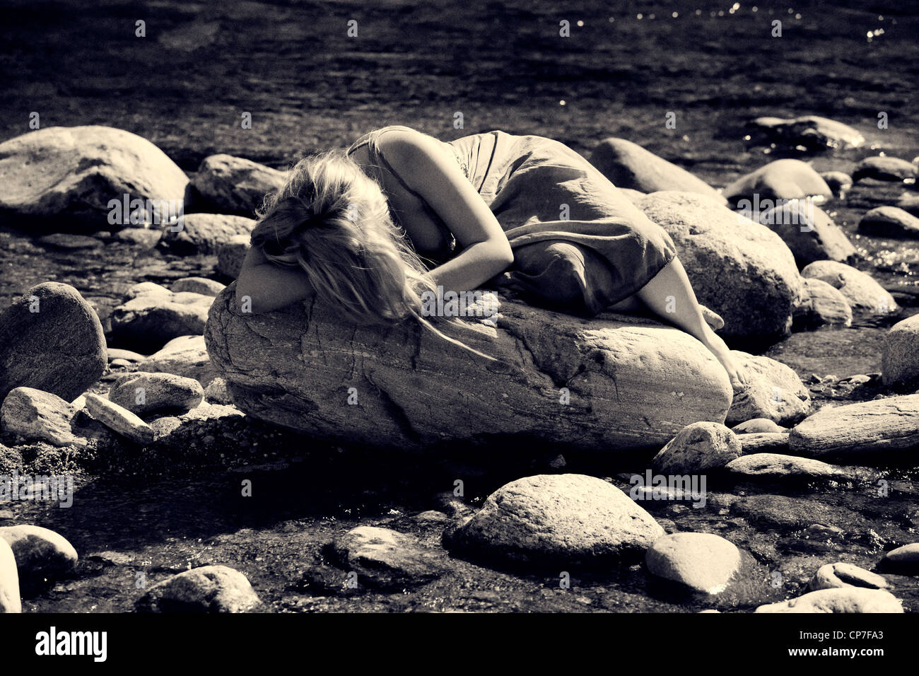 Giovane donna sdraiata su una roccia in un fiume Foto stock - Alamy