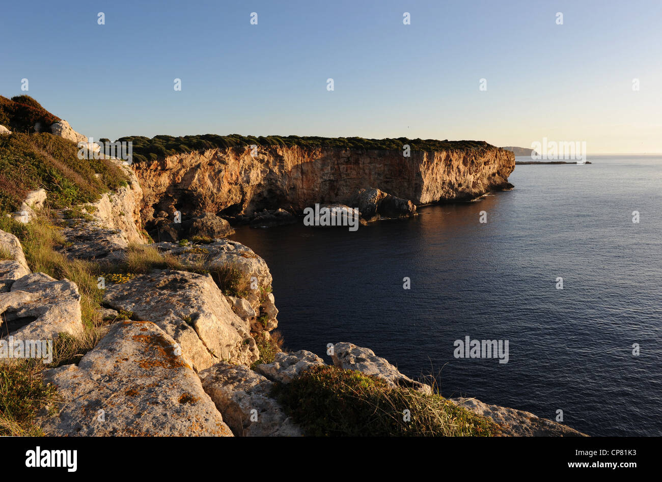 Menorca, Spagna, scogliere di Rafalet guardando verso l'entrata del porto di Mahon, nella distanza. Fotografia scattata a sunrise con un molto buon mare Foto Stock