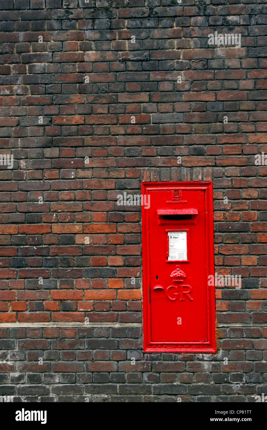 Red English Post Box in un muro di mattoni in Cambridge, Inghilterra Foto Stock