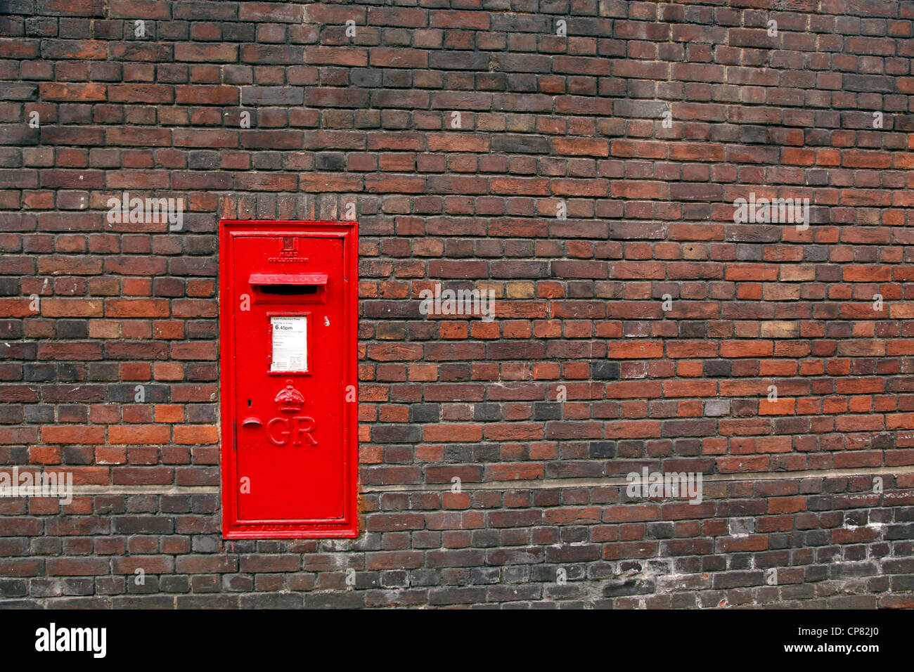 Red English Post Box in un muro di mattoni in Cambridge, Inghilterra Foto Stock