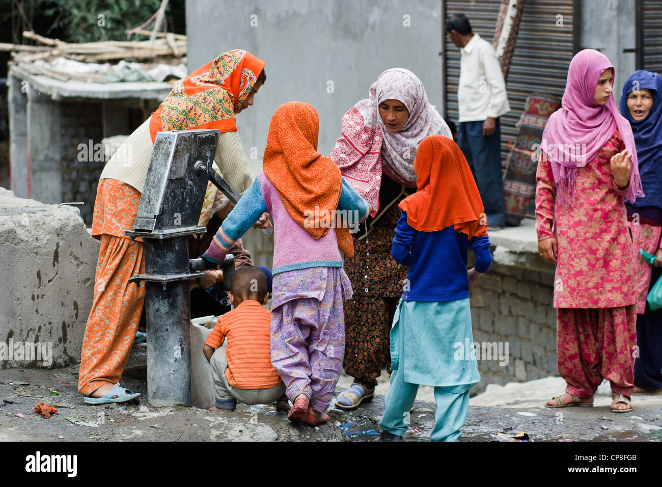 Un gruppo di donne musulmane e i bambini le benne di riempimento con acqua nella città di Kargil, stato di Jammu e Kashmir India Foto Stock