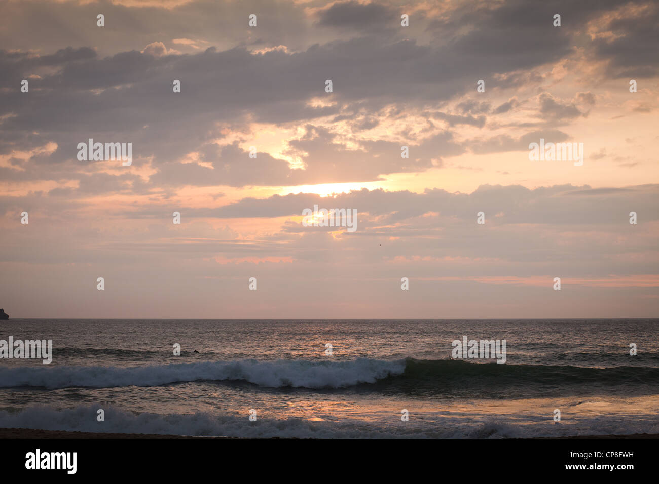 Tramonto sul mare acqua frizzante colori arancione drammatico sky sun dietro le nuvole Foto Stock
