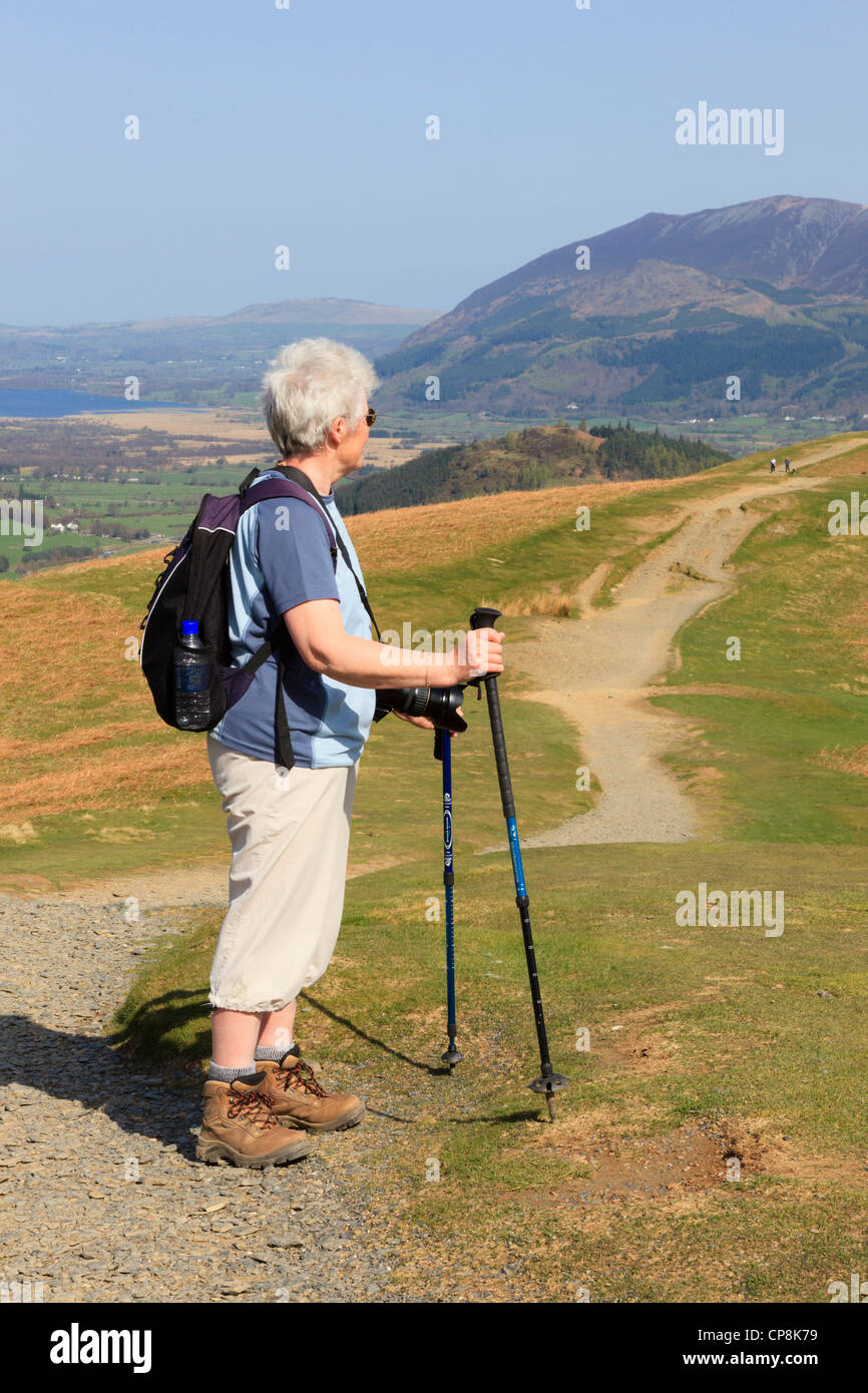 Senior donna utilizzando bastoncini per la camminata su un percorso fino Catbells nel Parco Nazionale del Distretto dei Laghi. Keswick Cumbira England Regno Unito Foto Stock