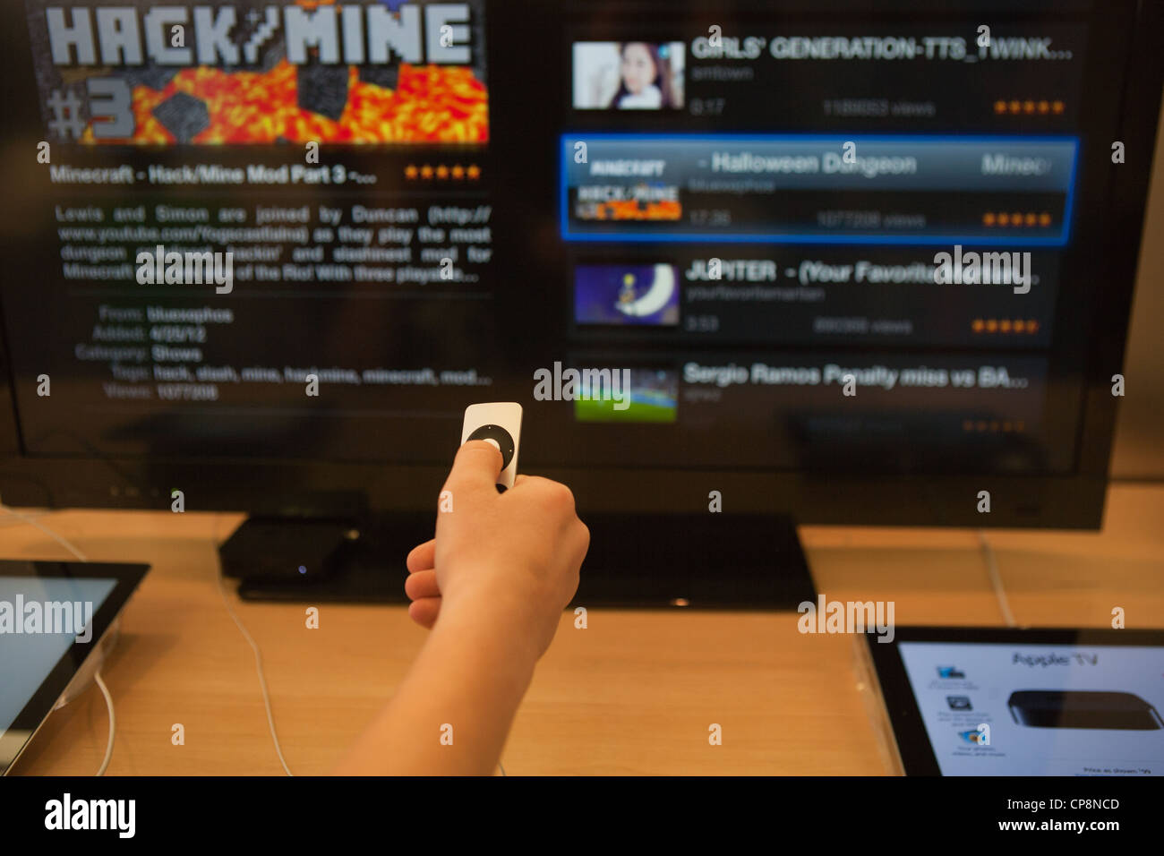 Il bambino fa una scelta per riprodurre video Minecraft gioco utilizzando Apple TV, grande schermo. Foto Stock