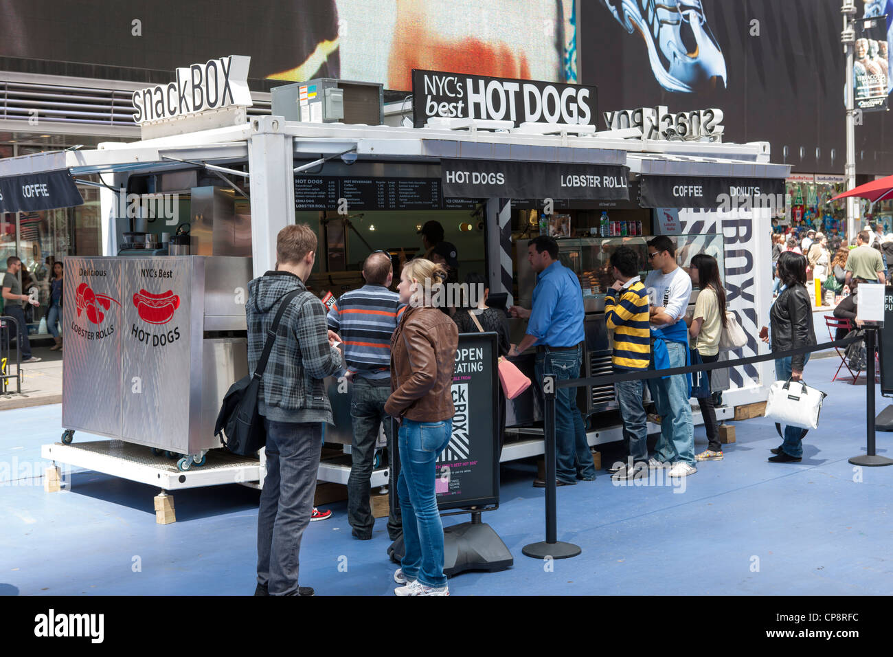 Le persone si mettono in linea per effettuare un acquisto presso lo snack Box, un alimento e bevanda chiosco in Times Square a New York City. Foto Stock