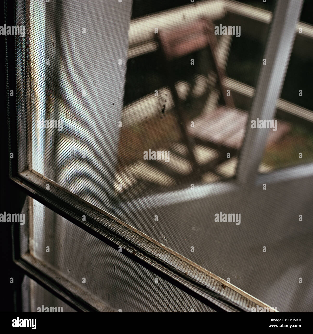 Sedia in legno sul ponte di legno visto attraverso la vecchia porta dello schermo Foto Stock