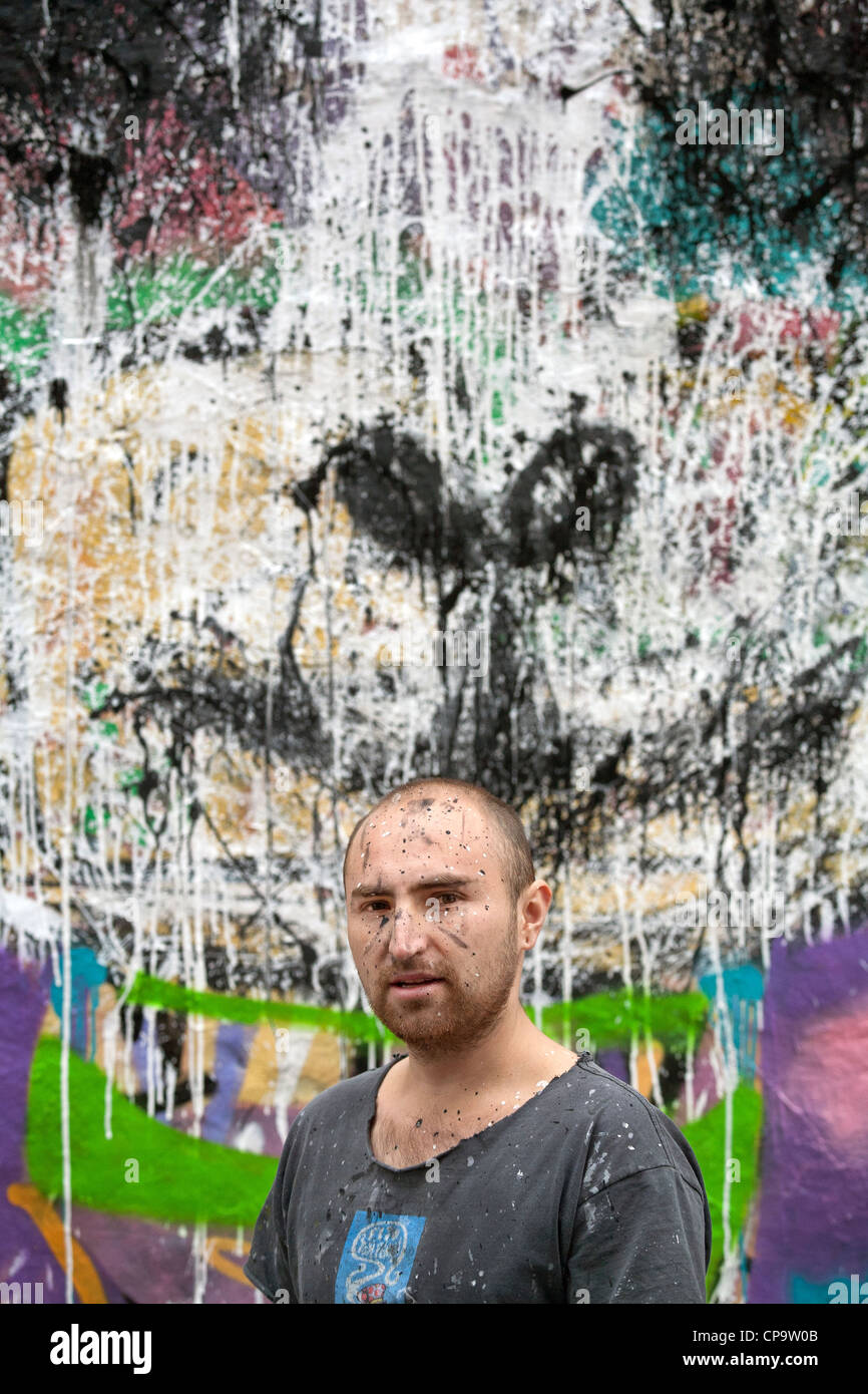 Ritratto di un giovane artista di graffiti di fronte ad uno dei suoi lavori in strada di Buenos Aires, Argentina Foto Stock