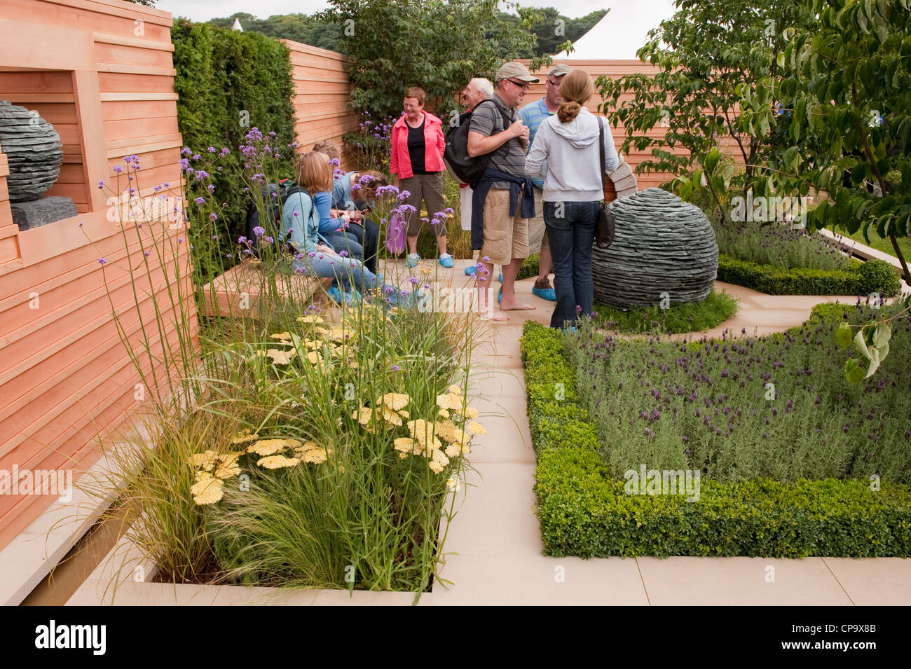 Le persone o i visitatori vista la scultura in pietra e piante medicinali in 'abbracciando il tranquility' garden - RHS Flower Show, Tatton Park, Cheshire, Inghilterra, Regno Unito. Foto Stock