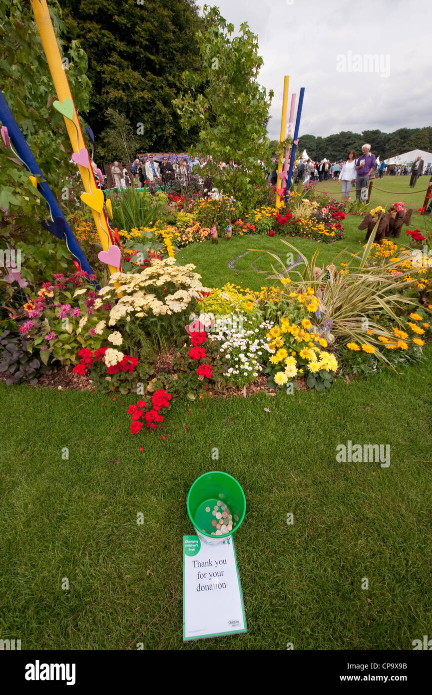 Benna di donazioni di denaro e i visitatori da bellissimi fiori colorati in NSPCC "sentire il nostro grido' show garden - RHS Flower Show, Tatton Park, Inghilterra, Regno Unito. Foto Stock