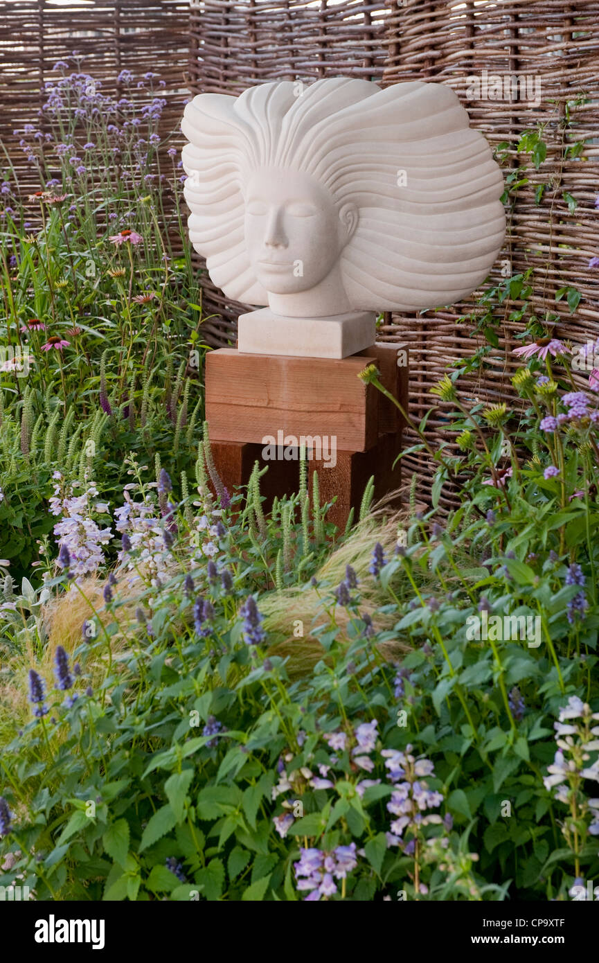 La scultura in pietra di testa è una funzione sul confine delle colorate fiori - 'Drisme solo sogni' mostrano giardino, RHS Flower Show, Tatton Park, England, Regno Unito Foto Stock