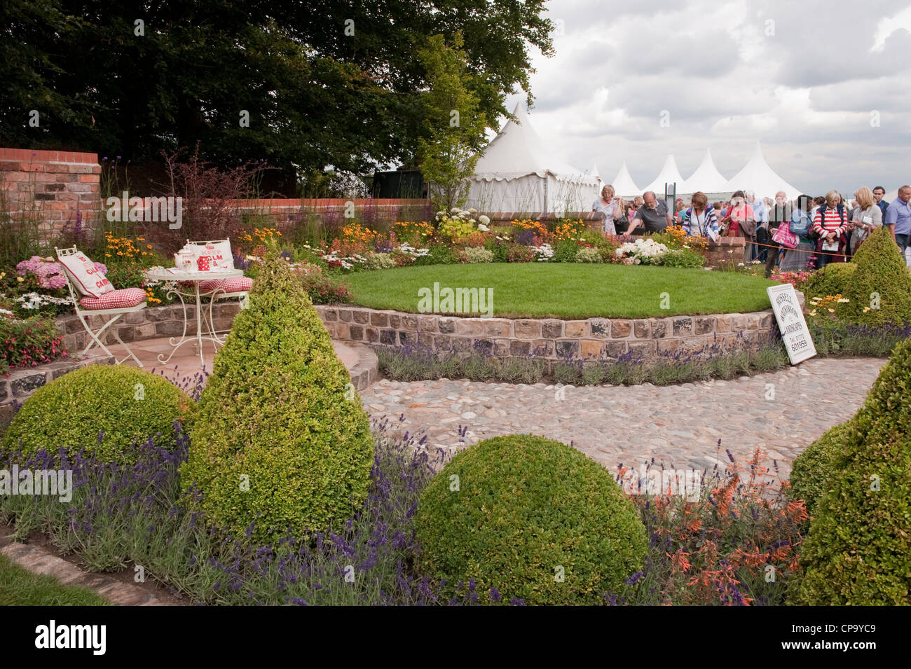Vista visitatori bellissimi fiori, prato e piccolo patio tranquilla area salotto in 'Serenity' mostra il giardino - RHS Flower Show, Tatton Park, Cheshire, Inghilterra. Foto Stock