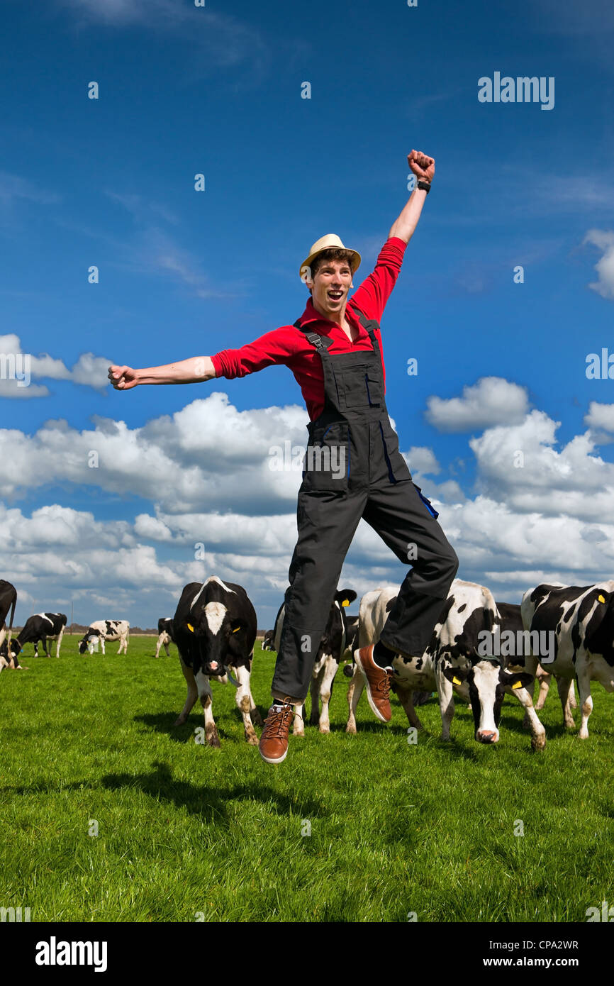 Felice giovane agricoltore il salto nel campo con le vacche Foto Stock