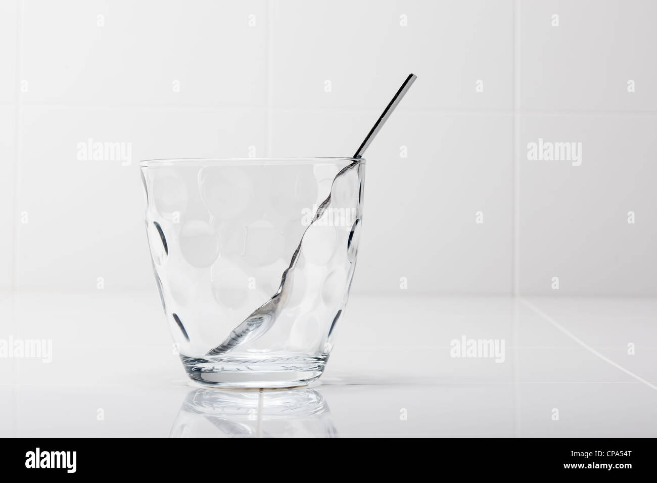 Un vetro trasparente tumbler con un argento cucchiaino in esso Foto Stock