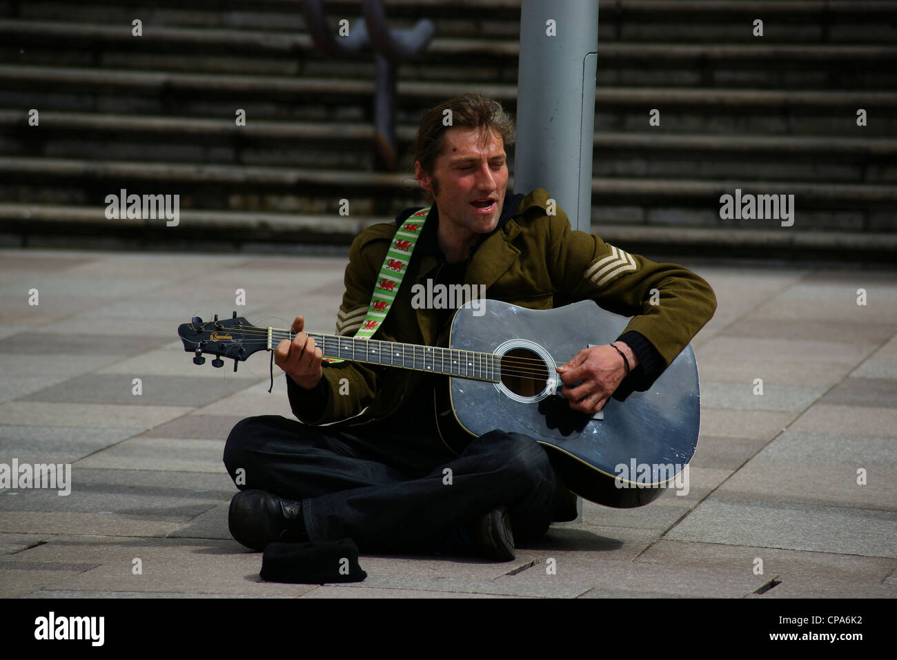 Busker suonare la chitarra per le strade di Cardiff Foto Stock