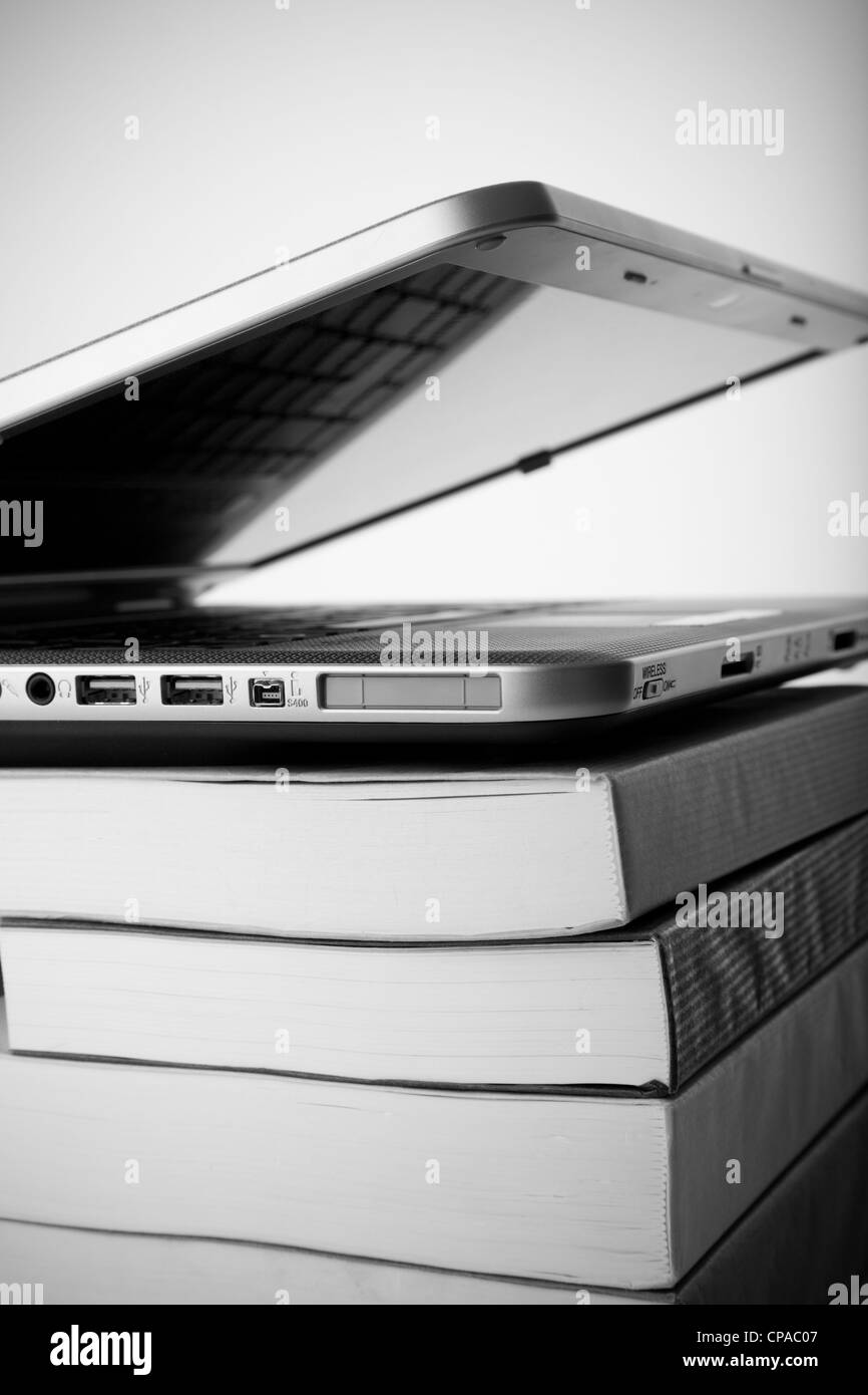 Libri colorati accanto a un laptop moderno Foto Stock