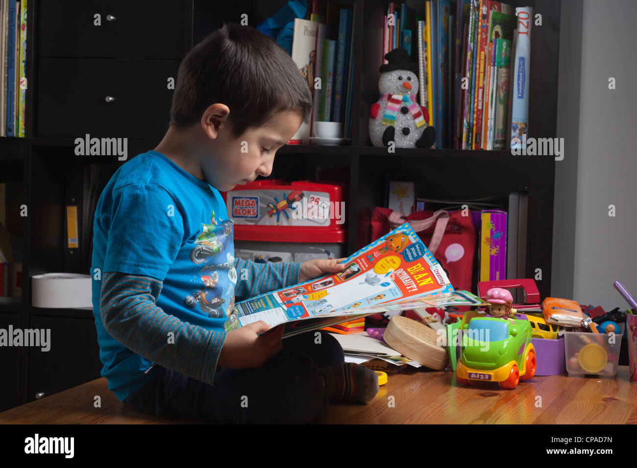 Ragazzo,4 anni legge un libro da colorare a casa Foto Stock
