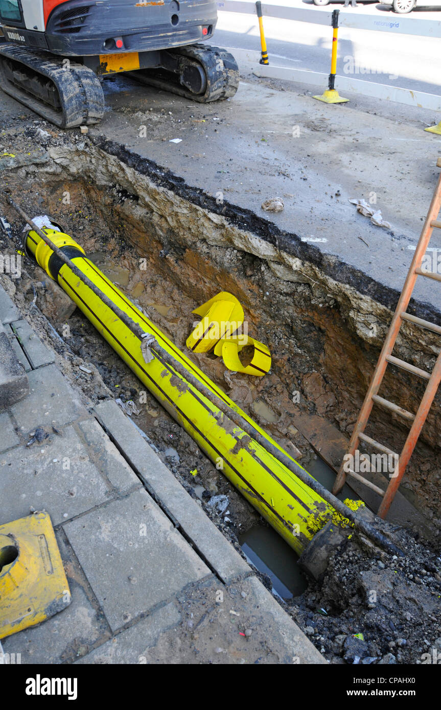 Sezione di vecchio tubo di ghisa rimosso spazio per il nuovo gas giallo di plastica di passare attraverso senza scavare più lavori stradali Shenfield Essex Inghilterra UK Foto Stock
