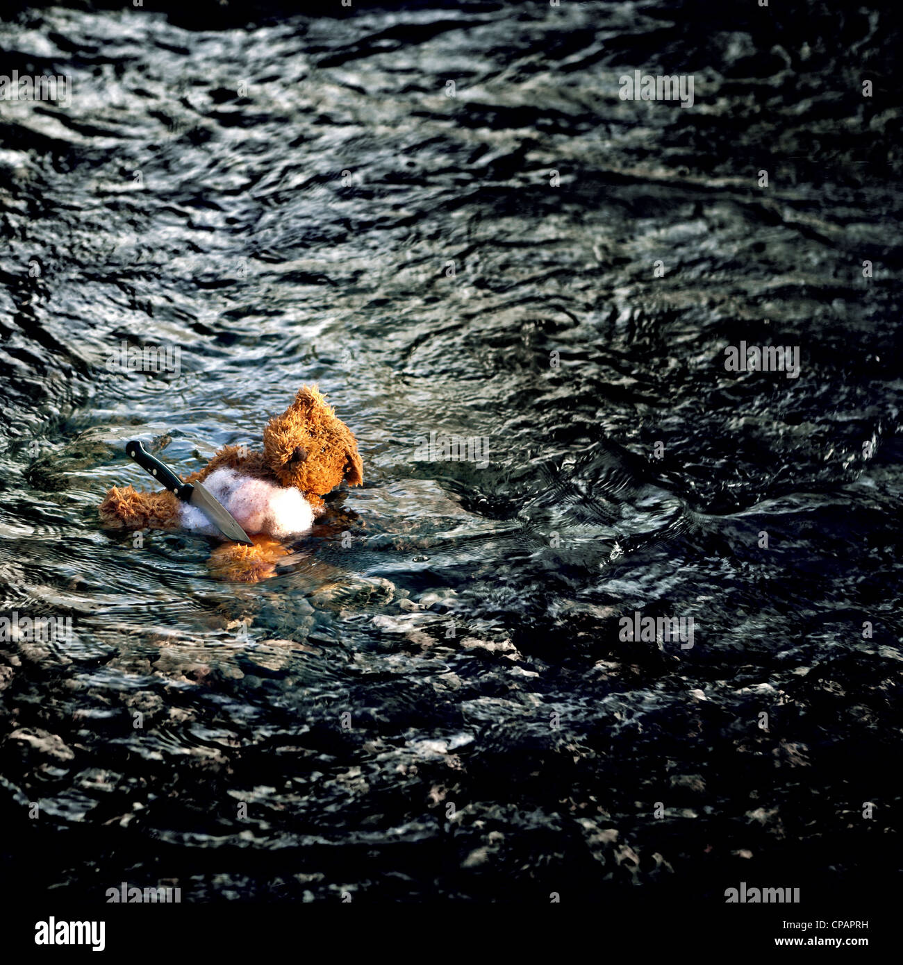 Un orsacchiotto in un fiume con un coltello Foto Stock