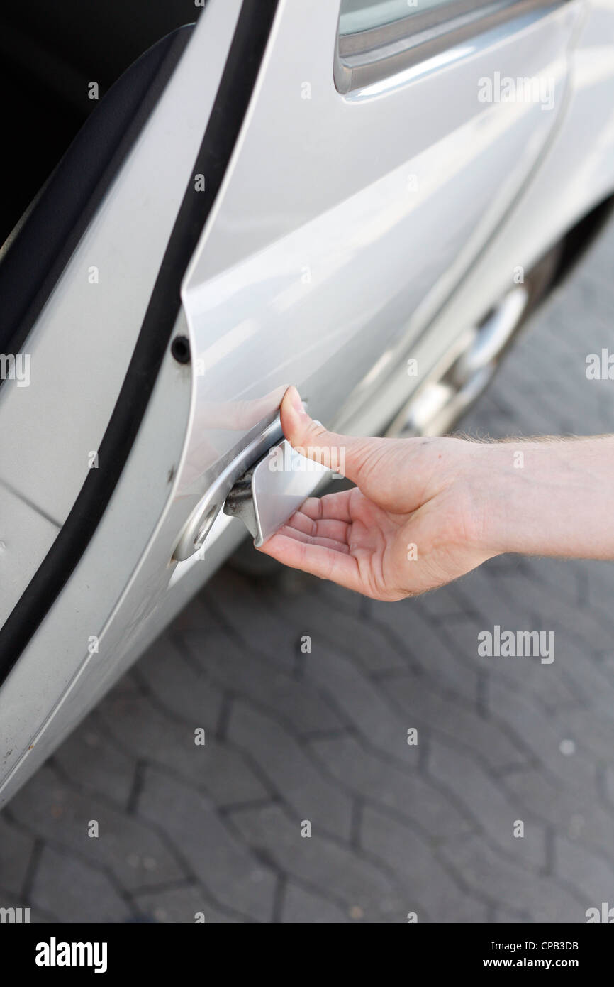 Una mano di aprire la portiera della macchina Foto Stock