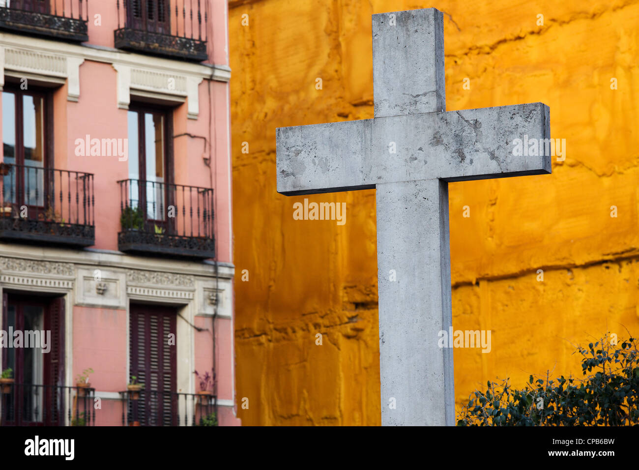 Primo piano su una croce di pietra realizzata nel 1738 contro un vivido arancione parete presso la Plaza de Puerta Cerrada a Madrid, Spagna. Foto Stock