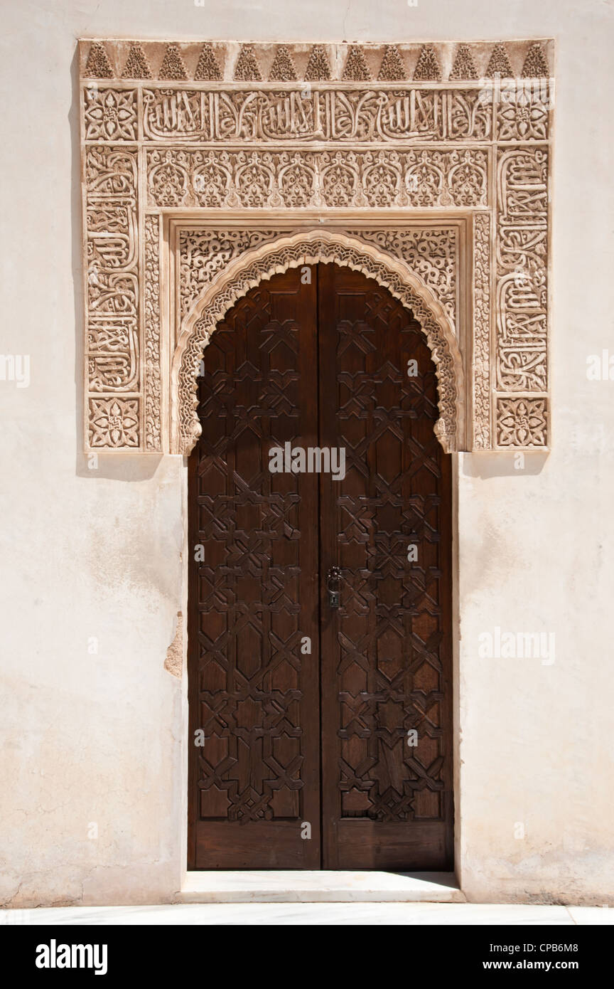 Ornata di rilievi che circondano un arcuato portale in legno nei palazzi Nasrid dell'Alhambra di Granada, Spagna. Foto Stock