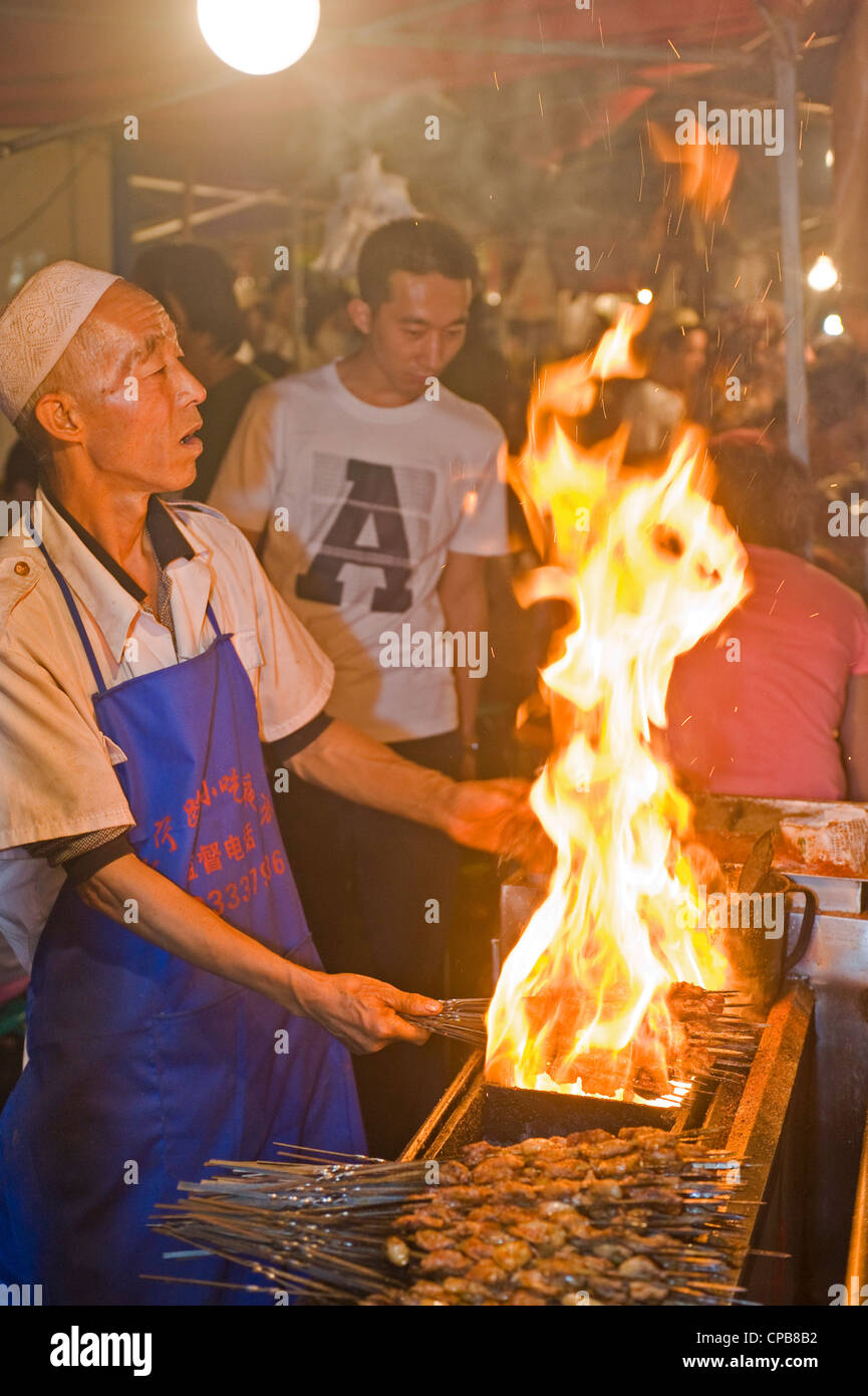 La preparazione di carne di manzo speziato bastoni/kebab snack alimentare alla ben nota Strada Zhengning notte food street market a Lanzhou. Foto Stock