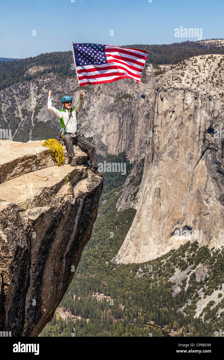Scalatore sul vertice sventola una bandiera americana. Foto Stock