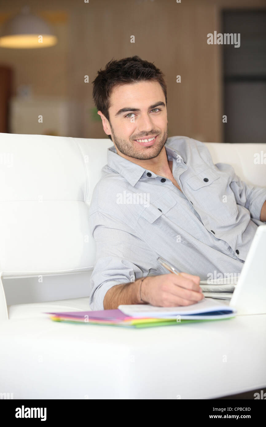 Uomo sorridente sul divano Foto Stock
