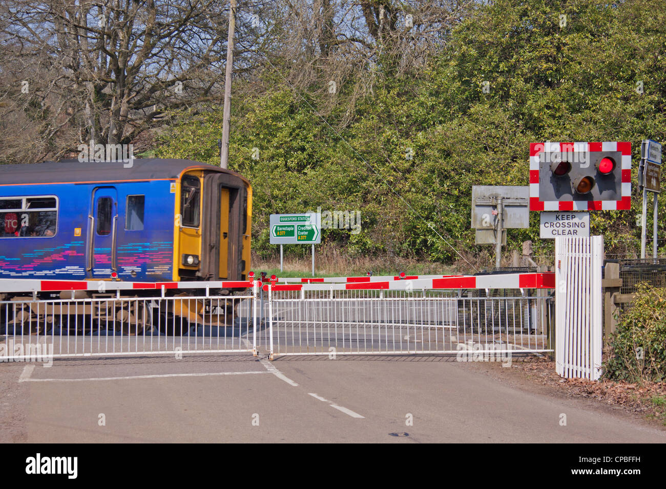 Treni passeggeri in Barnstaple - Exeter derivazione di linea che attraversa un unmanned passaggio a livello fuori Eggesford stazione in Devon UK Foto Stock