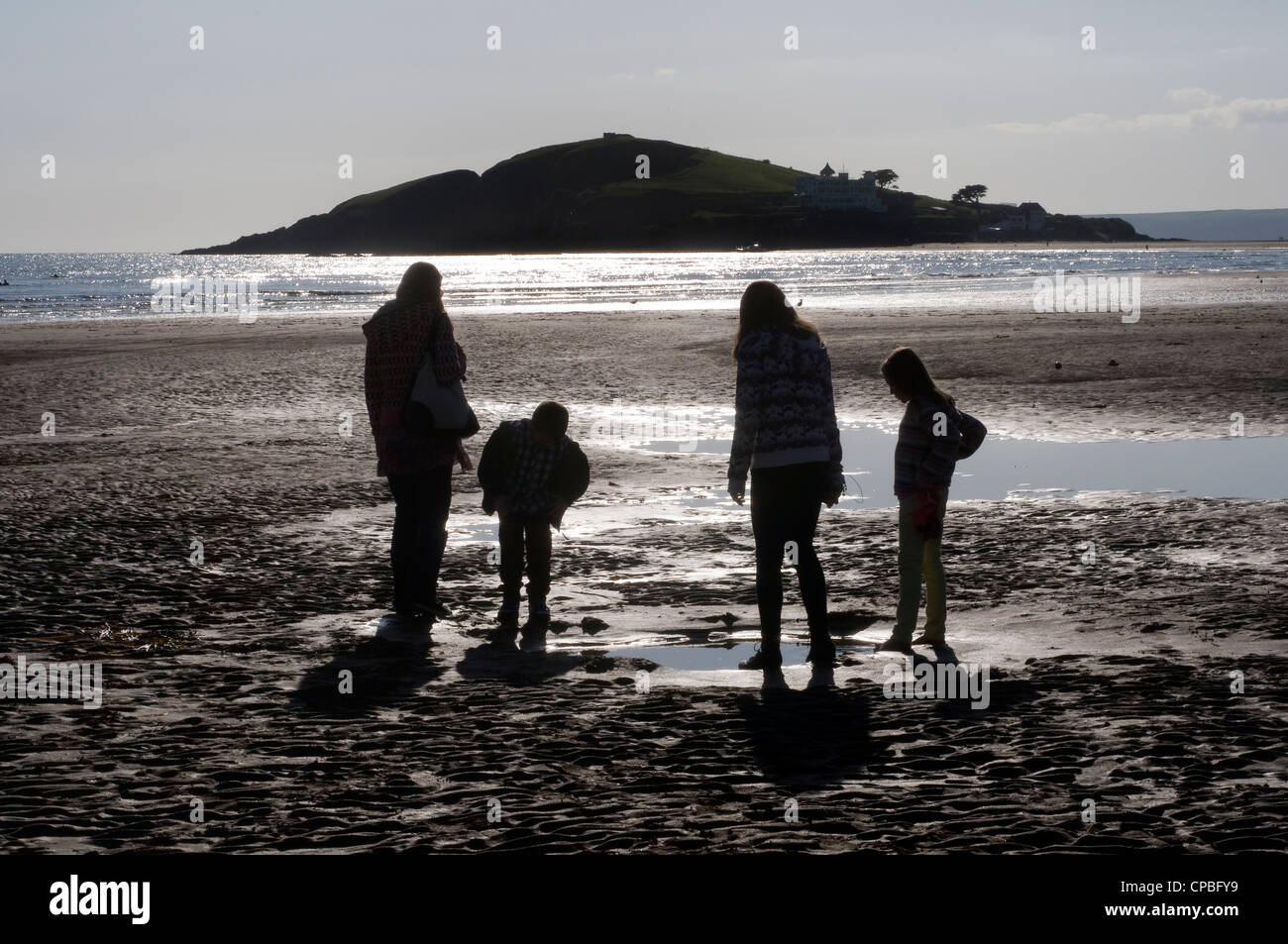 Famiglia guardando rock pool a Bantham Bay con Burgh Island,villaggio di Bantham presso la foce del fiume Avon,South Hams,devon Foto Stock