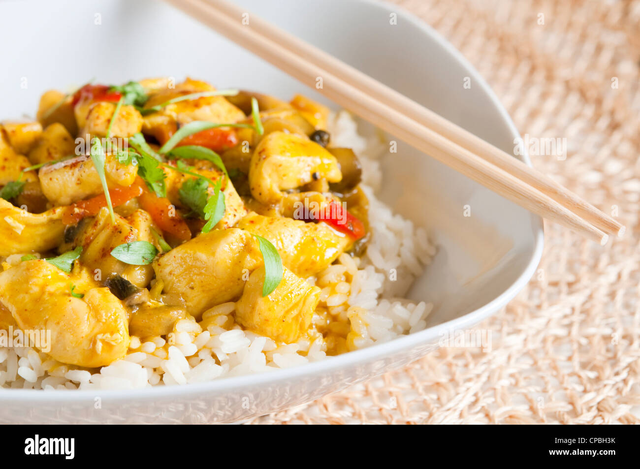 Pollo al curry in una ciotola bianca con bacchette Foto Stock