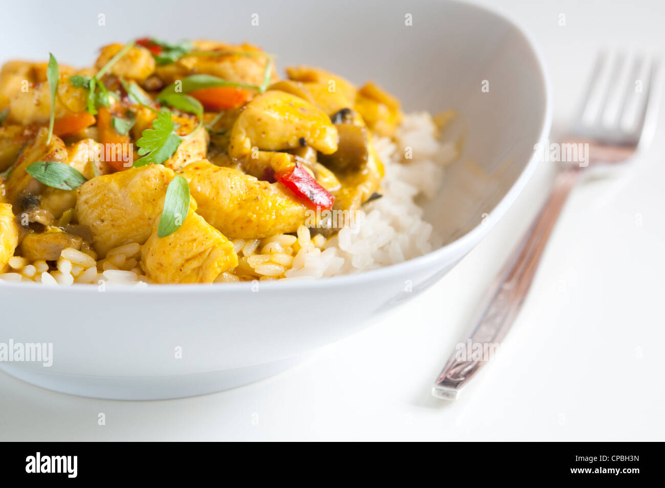 Pollo al curry in una ciotola bianca con forca Foto Stock