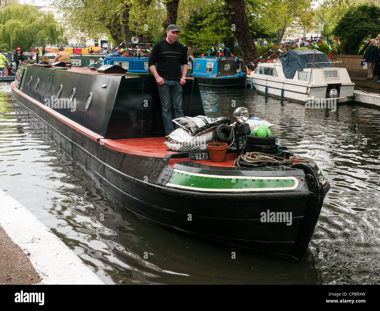 Uomo in piedi su una piccola imbarcazione in un Festival sul Grand Union Canal in Little Venice, Paddington, West London, Regno Unito Foto Stock