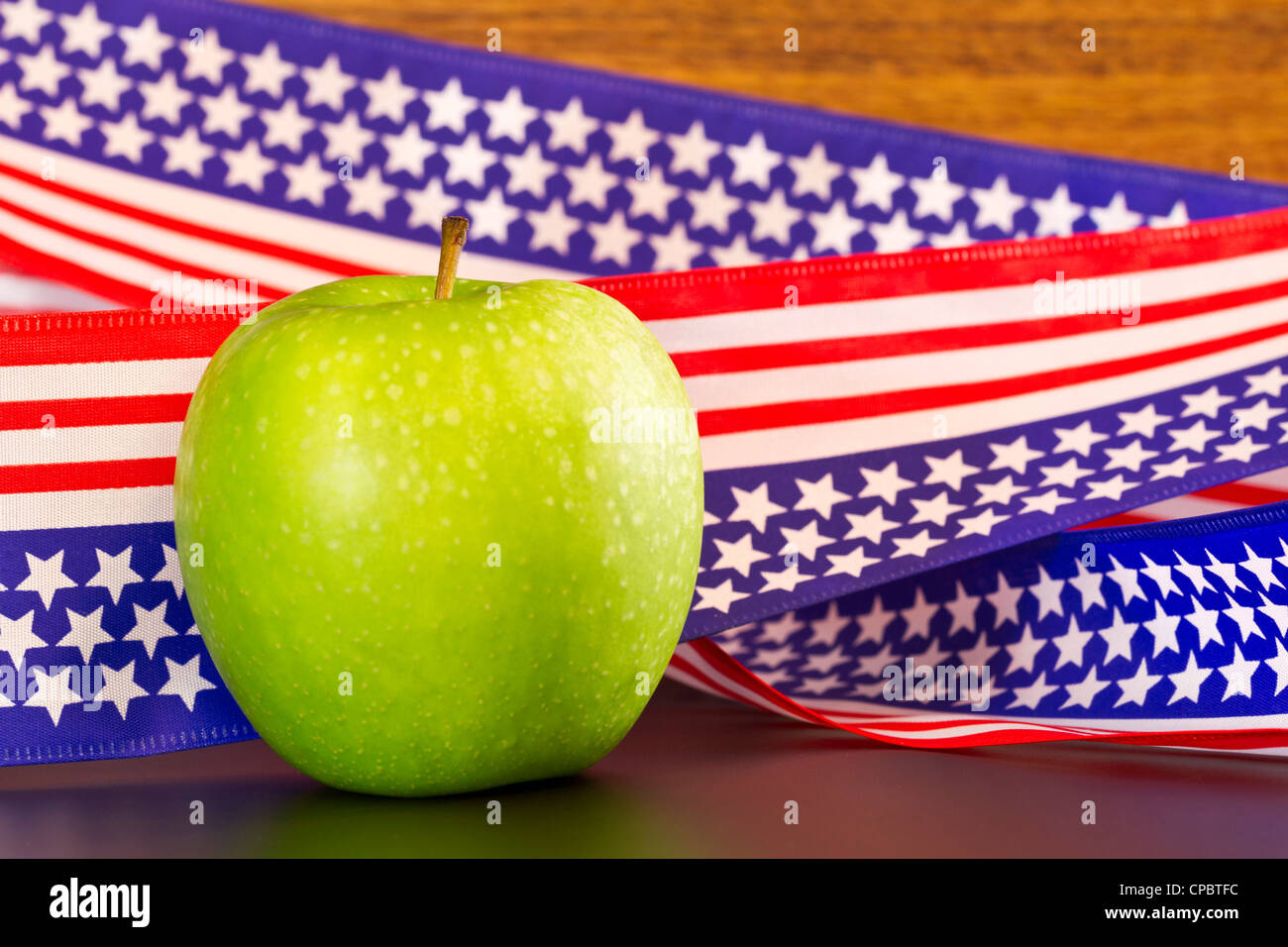 Mela verde posto davanti a stelle e strisce di nastro che preleva sulla bandiera degli Stati Uniti motif; Apple suggerisce la scuola, l'istruzione. Foto Stock