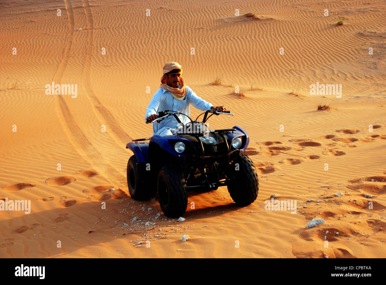 Locale nazionale araba in sella a una moto quad nel deserto di Dubai, UAE Foto Stock