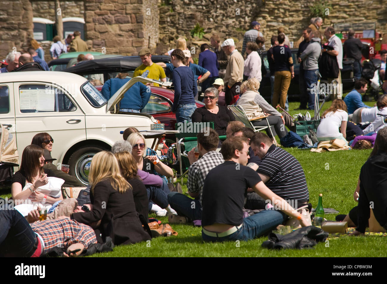La folla rilassarsi e godersi il sole a marche Trasporti Festival esposizione di vintage e classic cars in mostra a molla di Ludlow Food Festival Foto Stock