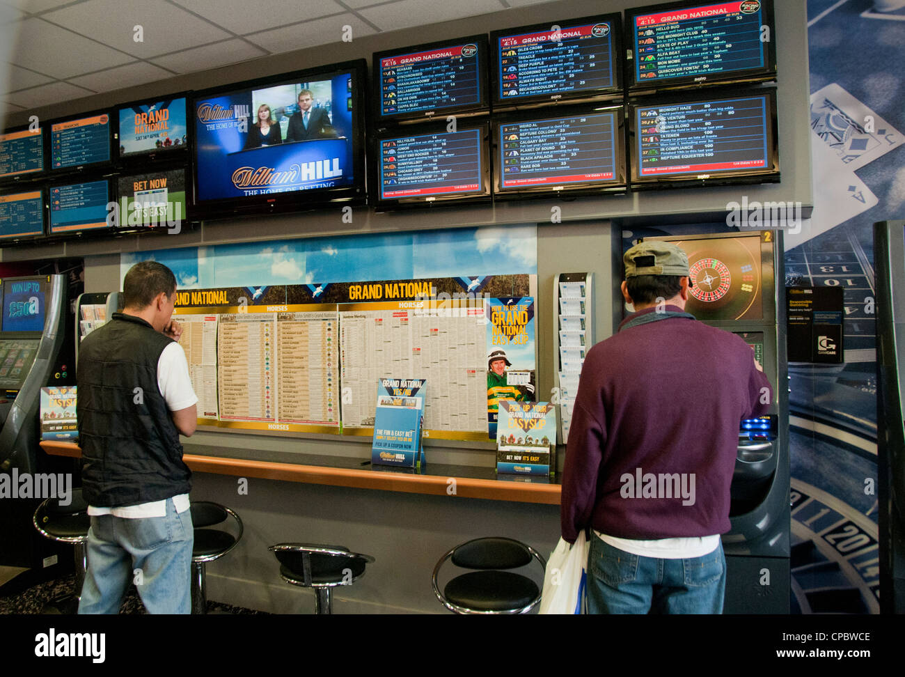 Persone in negozio di scommesse piazzare scommesse durante il Grand National corsa di cavalli Foto Stock