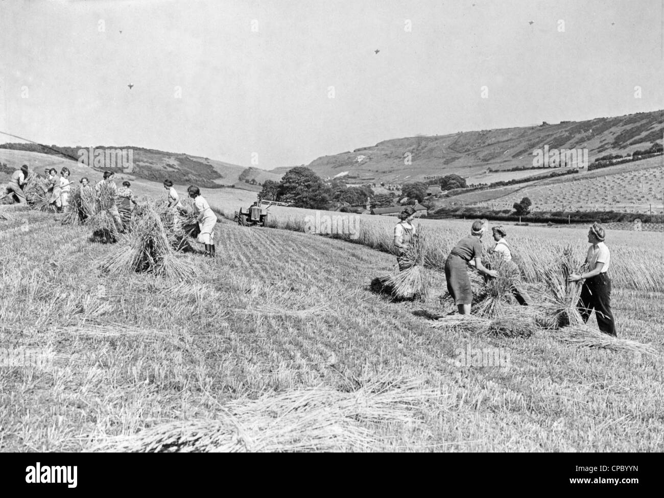 Nell esercito ragazze e famiglie lavorando sul raccolto in tempo di guerra la Gran Bretagna. Questa foto è stata scattata nel 1942 vicino alla costa del Kent e palloncini di Barrage può essere visto nel cielo. Foto Stock