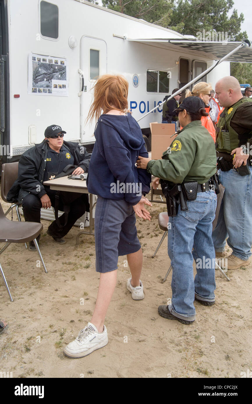 Sheriff's deputati arrestare un senzatetto donna su un eccezionale garantisce in Victorville, CA, durante la ricerca di un accampamento. Foto Stock