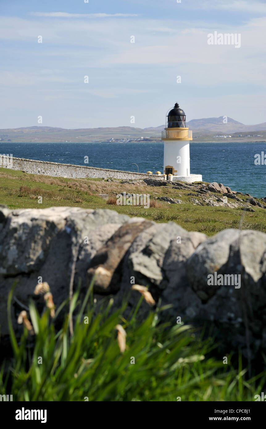 Luce di casa sulla costa di Islay, Isle of Jura in background, muro di pietra in primo piano Foto Stock