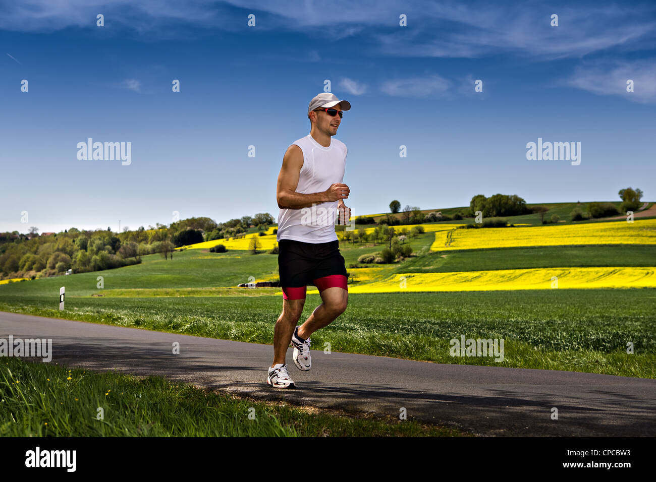 Un giovane uomo jogging attraverso i campi Foto Stock