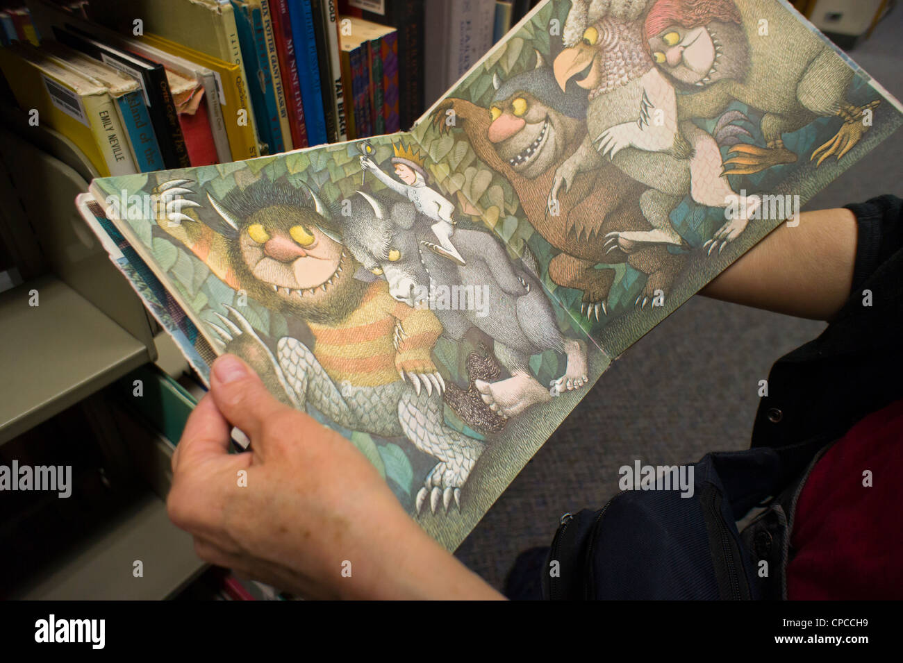 Un lettore esplora un ben indossati copia di Maurice Sendak il famoso 1963 libro per bambini, "dove le cose selvagge sono' Foto Stock