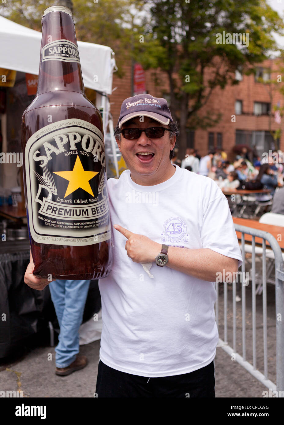 Un uomo con una grande Sapporo gonfiabile di bottiglia di birra - USA Foto Stock