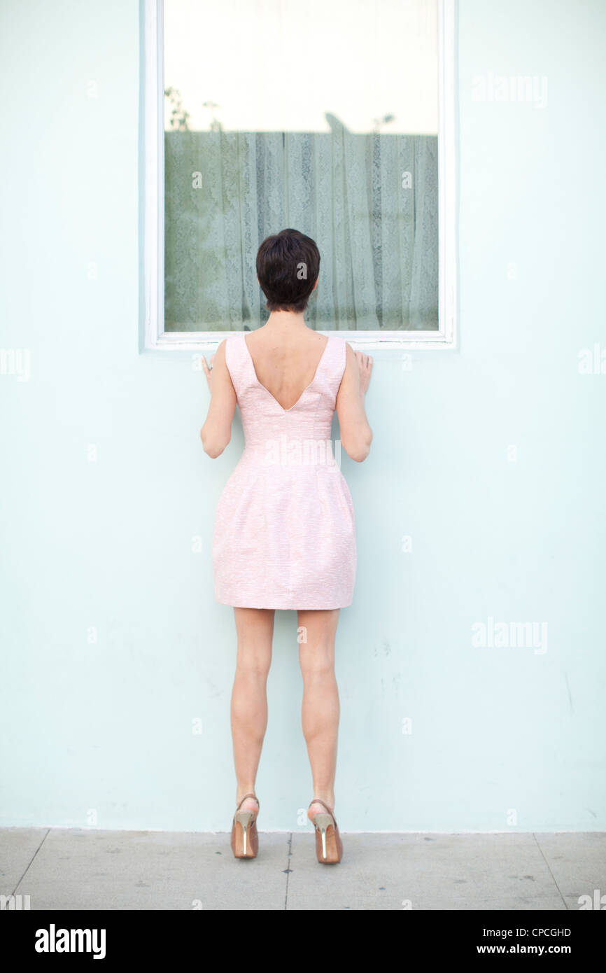 Donna che guarda in una finestra Foto Stock