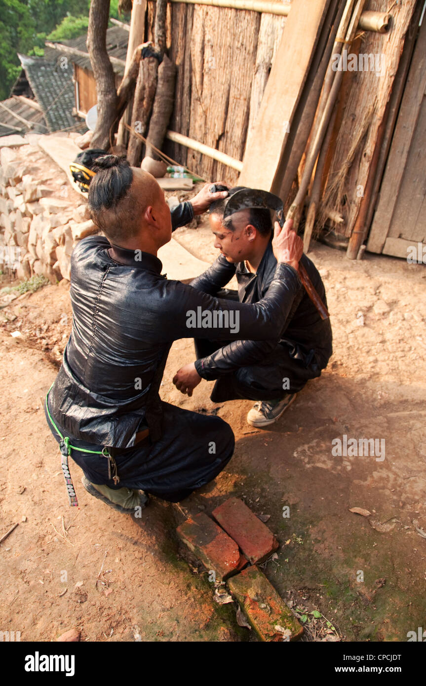 Un giovane basha miao (pistola uomini) uomo avente il suo pelo rasato da un falcetto, Cina del Sud Foto Stock Un giovane basha miao (pistola uomini) uomo avente il suo pelo rasato da un falcetto, Cina del Sud Foto Stock