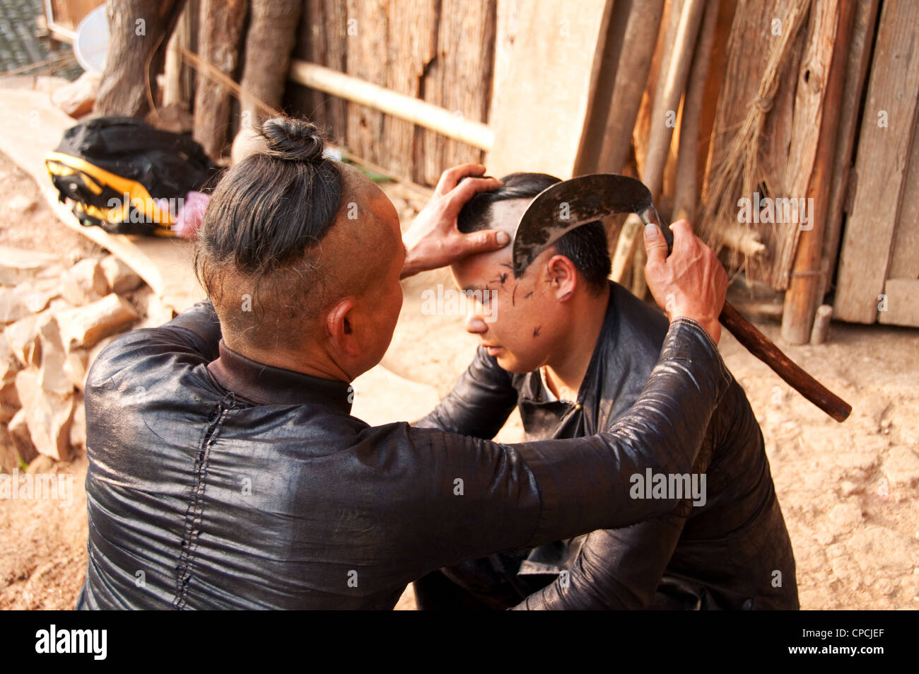Un giovane basha miao (pistola uomini) uomo avente il suo pelo rasato da un falcetto, Cina del Sud Foto Stock Un giovane basha miao (pistola uomini) uomo avente il suo pelo rasato da un falcetto, Cina del Sud Foto Stock