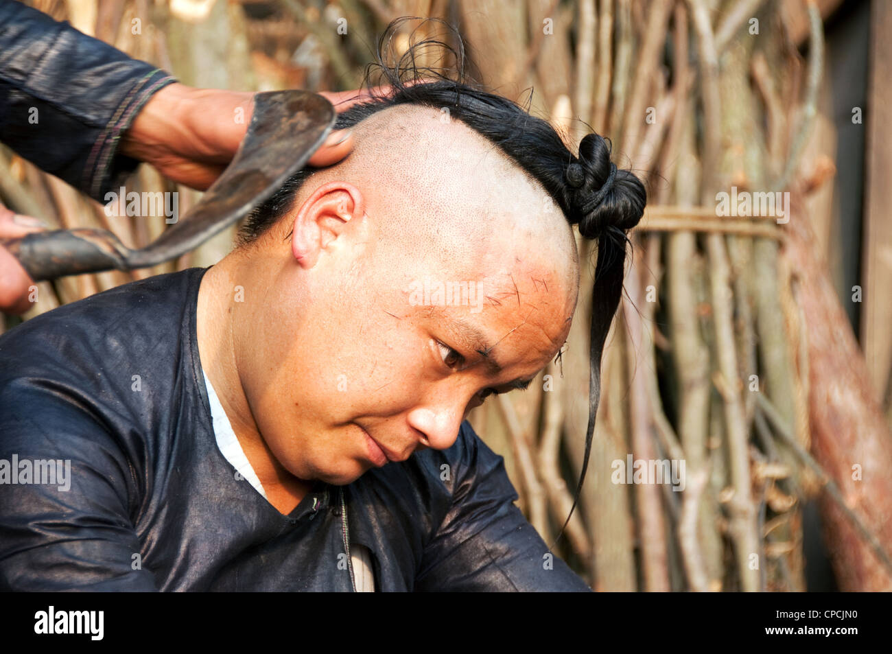 Un giovane basha miao (pistola uomini) uomo avente il suo pelo rasato da un falcetto, Cina del Sud Foto Stock Un giovane basha miao (pistola uomini) uomo avente il suo pelo rasato da un falcetto, Cina del Sud Foto Stock