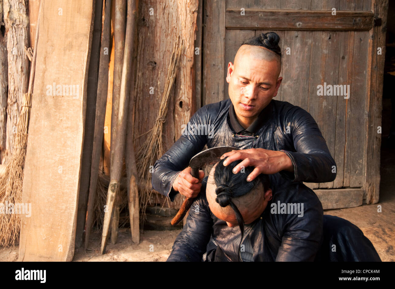 Un giovane basha miao (pistola uomini) uomo avente il suo pelo rasato da un falcetto, Cina del Sud Foto Stock Un giovane basha miao (pistola uomini) uomo avente il suo pelo rasato da un falcetto, Cina del Sud Foto Stock