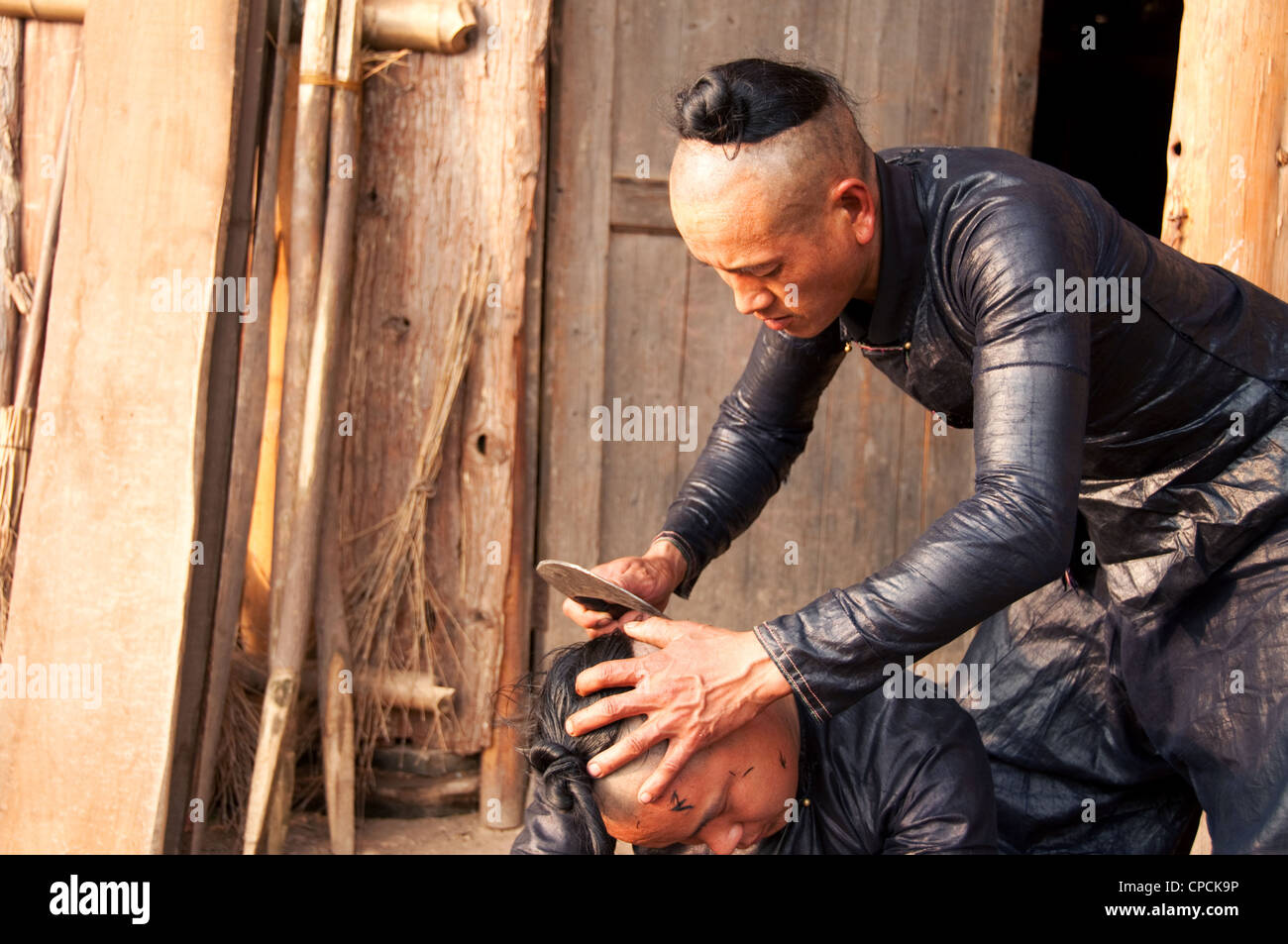 Un giovane basha miao (pistola uomini) uomo avente il suo pelo rasato da un falcetto, Cina del Sud Foto Stock Un giovane basha miao (pistola uomini) uomo avente il suo pelo rasato da un falcetto, Cina del Sud Foto Stock